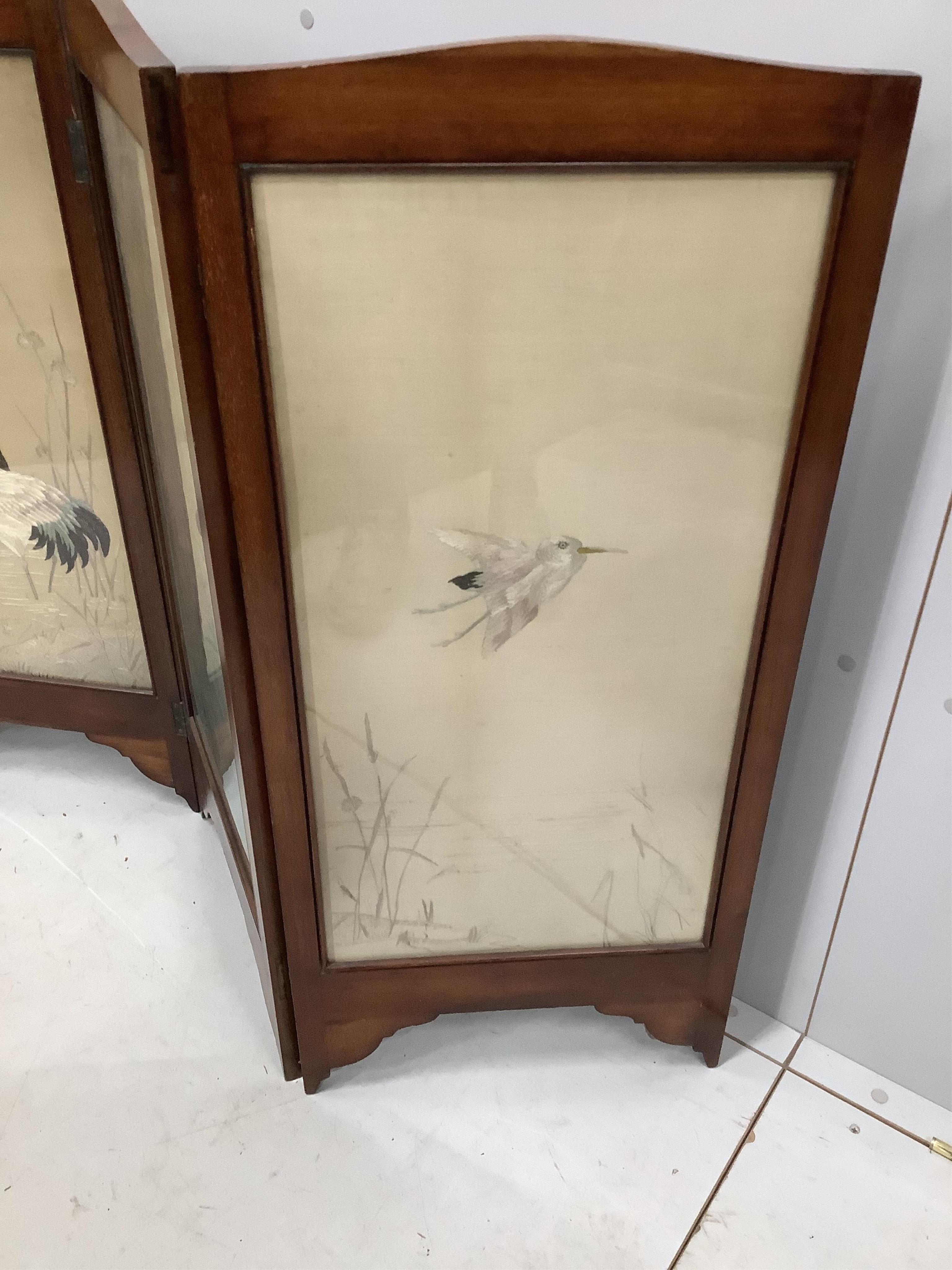 An early 20th century silk thread embroidered four fold table screen, decorated with birds among reeds, each panel width 41cm, height 94cm. Condition - fair